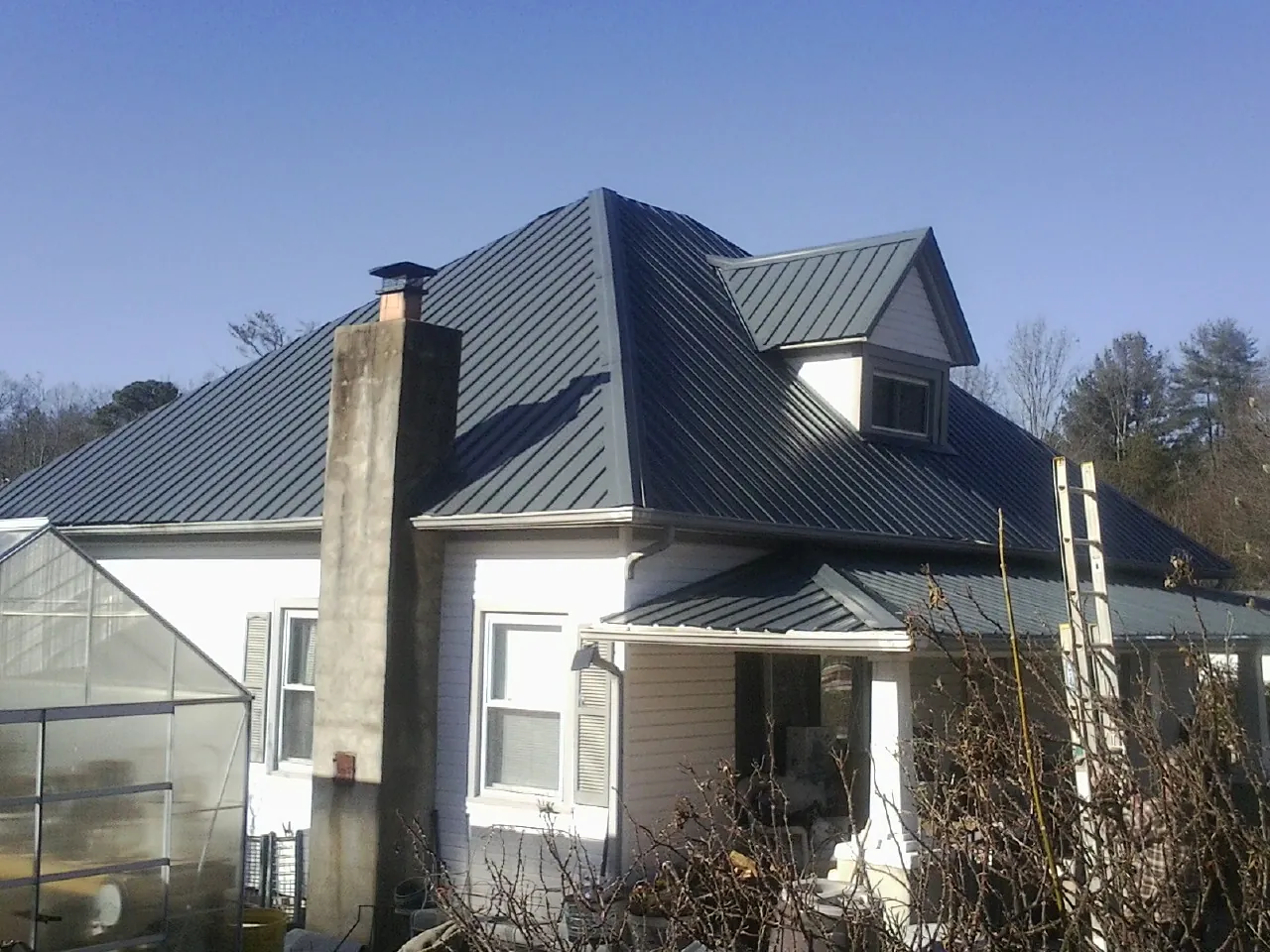 Dark blue standing seam metal roof on a white farmhouse with dormer — Slate & Tile Roof Repair by Roofing Brothers in Narragansett