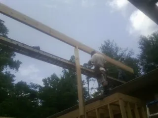 Carpenter setting a ridge beam over a new addition frame — Ice Dam Removal by Roofing Brothers in Narragansett