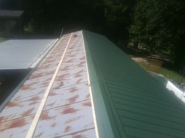 Old rusted panels beside newly installed green metal roofing — Wind Damage Roof Repair by Roofing Brothers in Narragansett