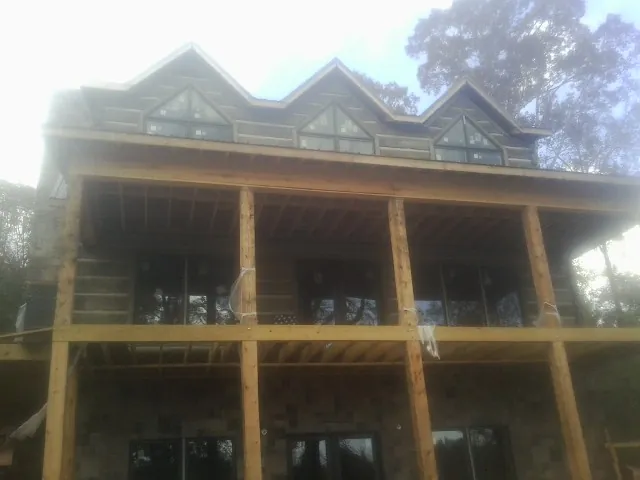 Dormers and porch framing on a large log home under construction — Roof Coating work by our crew in Narragansett