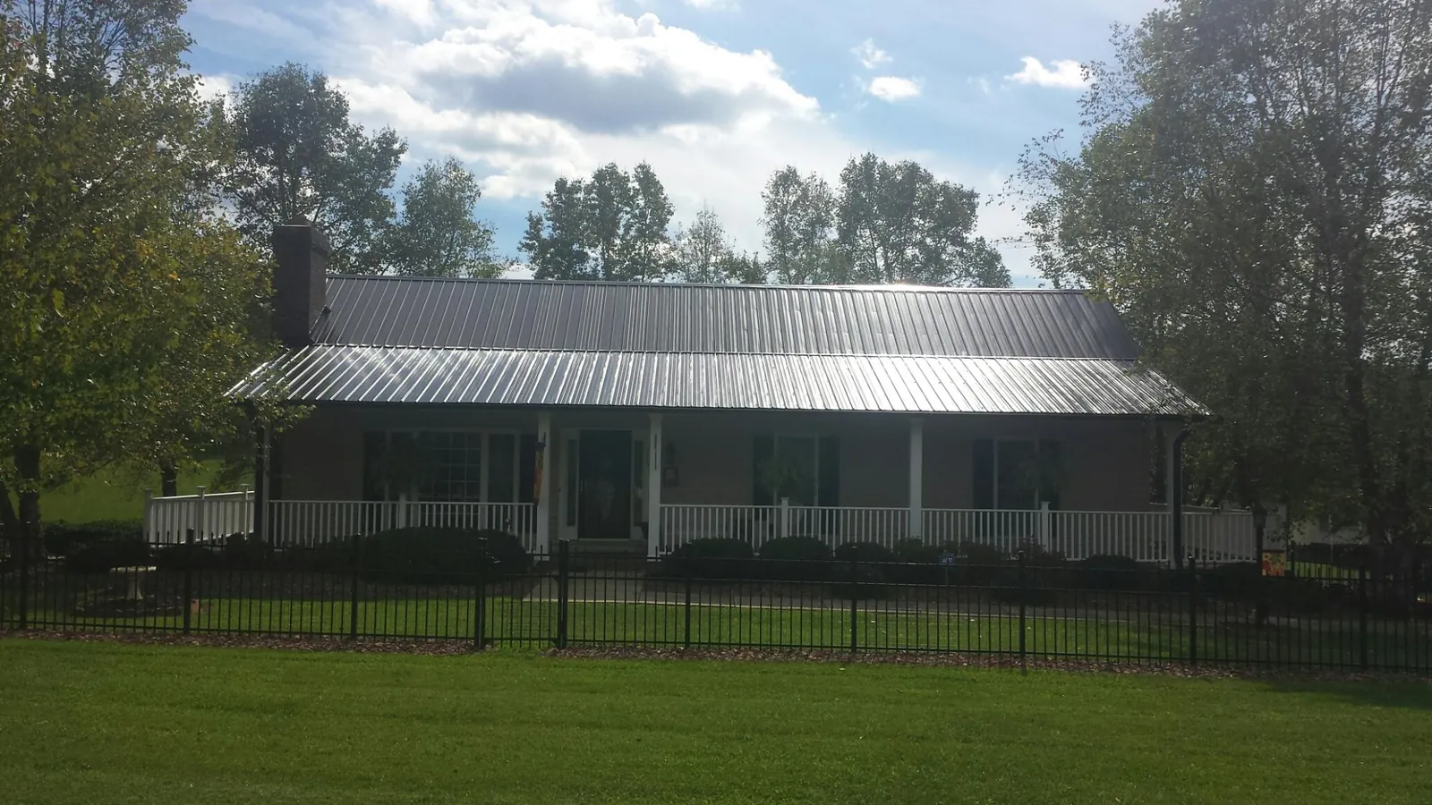 Gray metal roof on a brick ranch with a full width front porch — Gutter Guard Installation work by our crew in Narragansett
