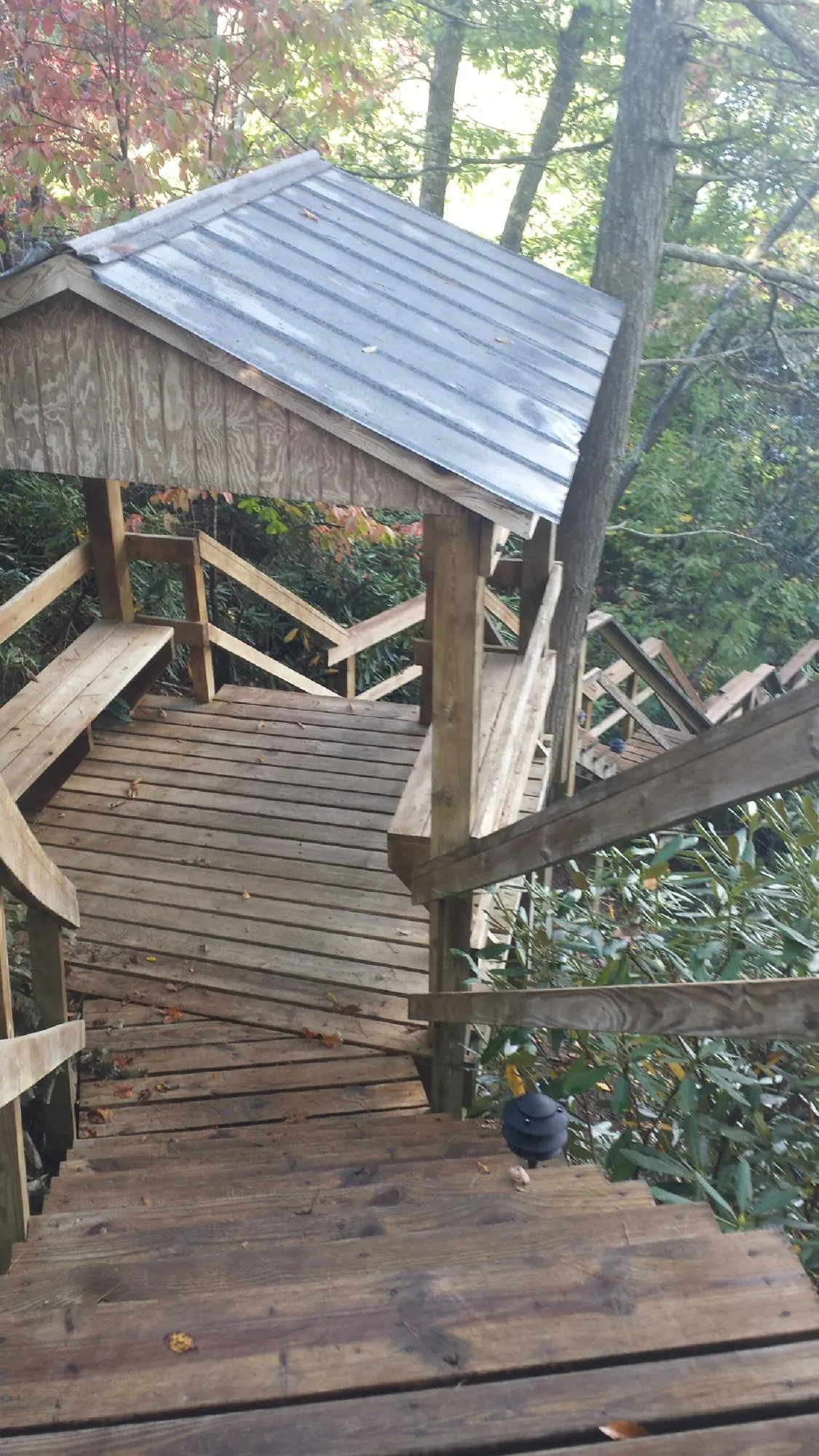 Metal roofed shelter over wooden steps on a wooded walkway — Skylight Repair & Installation work by our crew in Narragansett