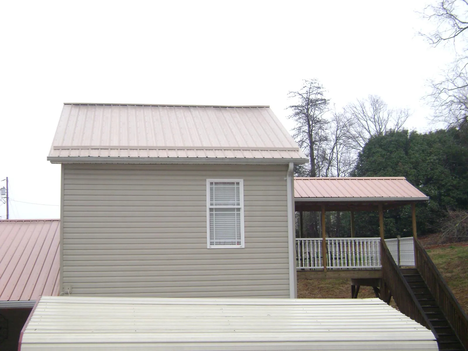 Tan metal roofs on a two story addition and attached porch, from a Roof Replacement job in Narragansett